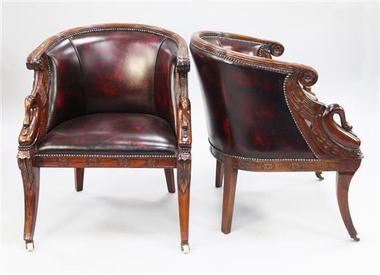 A pair of French Empire style carved mahogany and brass studded leather tub shaped armchairs,